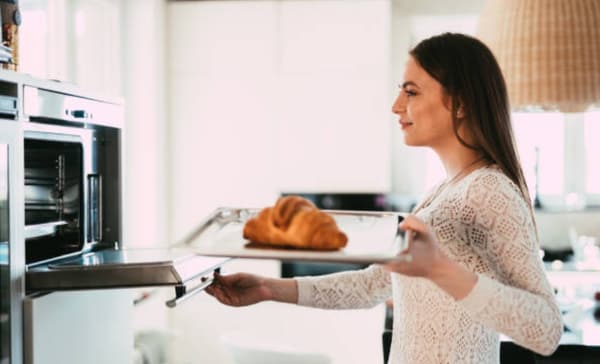 A woman inserting a baked item into an oven A woman inserting a baked item into an oven